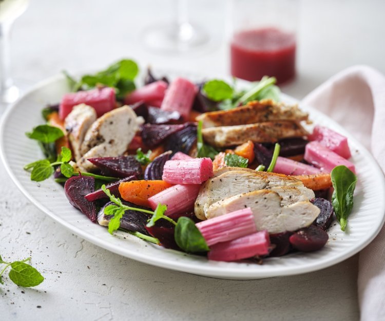 Een rijkgevuld salade die gezond is en mooi van kleur, daar word je instant vrolijk van. De salade bestaat uit frisgroene spinazie, warmoranje wortel, bloedrode bietjes, zoetroze rabarbar en goudgegrilde kip. De frambozendressing werd erbij geserveerd in een glazen kannetje. 