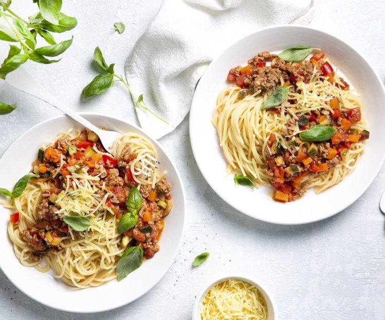 Spaghetti bolognaise Twee borden gevuld met huisgemaakte spaghetti bolognaise. Afgewerkt met basilicumblaadjes die zorgen voor extra smaak en kleur in je bord.