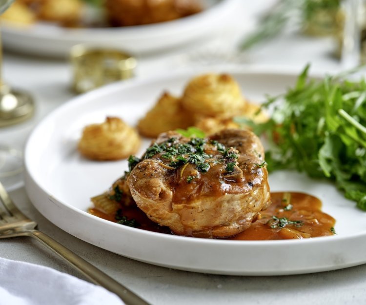 Het hoofdgerecht is geserveerd op een wit groot bord. Ieder krijgt een portie schenkel, pommes duchesse en frisse rucolasla. 