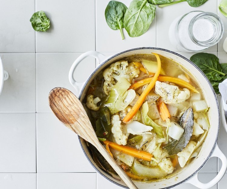 Stoofpotje van bloemkool, wortel en koolrabi Een lentestoofpotje boordevol groenten, denk maar aan bloemkool, wortel, koolrabi, prei en spinazie. De stoofpot staat op het aanrecht in een grote kookpot, rond de pot liggen nog enkele spinazieblaadjes en een flesje room.