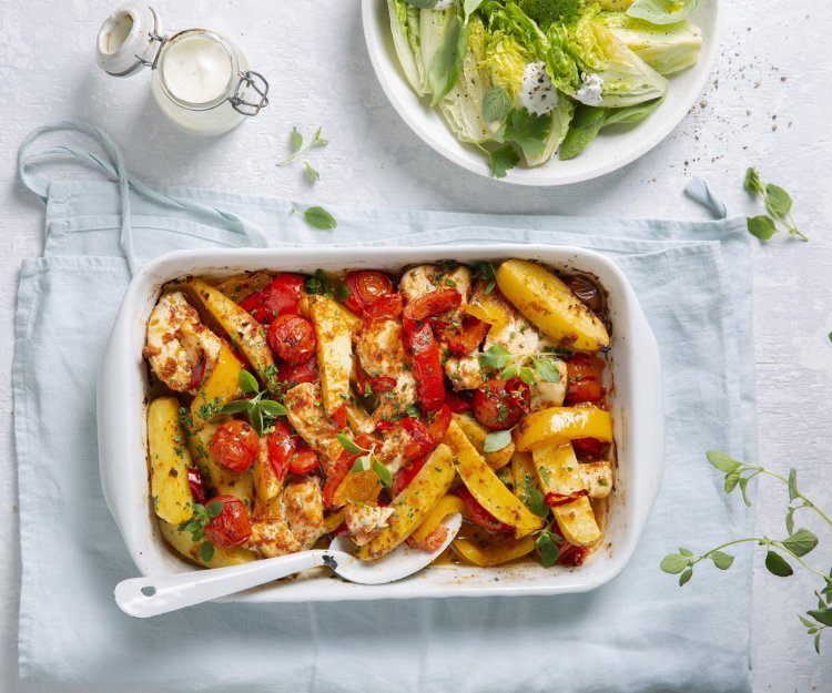 Een heerlijke hoofdmaaltijd in één ovenschaal met stukjes aardappel, tomaten, paprika en kip. Er is ook een knapperige salade van little gem met yoghurtdressing.