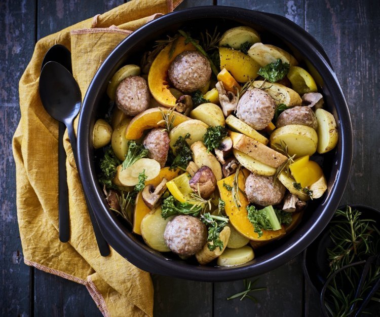 Traybake van aardappelen, pompoen, boerenkool en gehaktballetjes Een heerlijke kleurrijke traybake boordevol herfsttoppers. In een zwarte ronde ovenschotel werd een traybake klaargemaakt met aardappelblokjes, stukjes pompoen, boerenkool en gehaktballetjes.