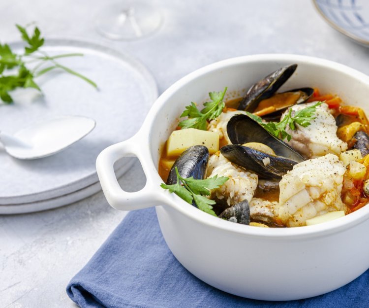 Een stoofpotje van vis, mosselen en passata klaargemaakt in een grote witte kookpot. Vakantie in je kookpot! 