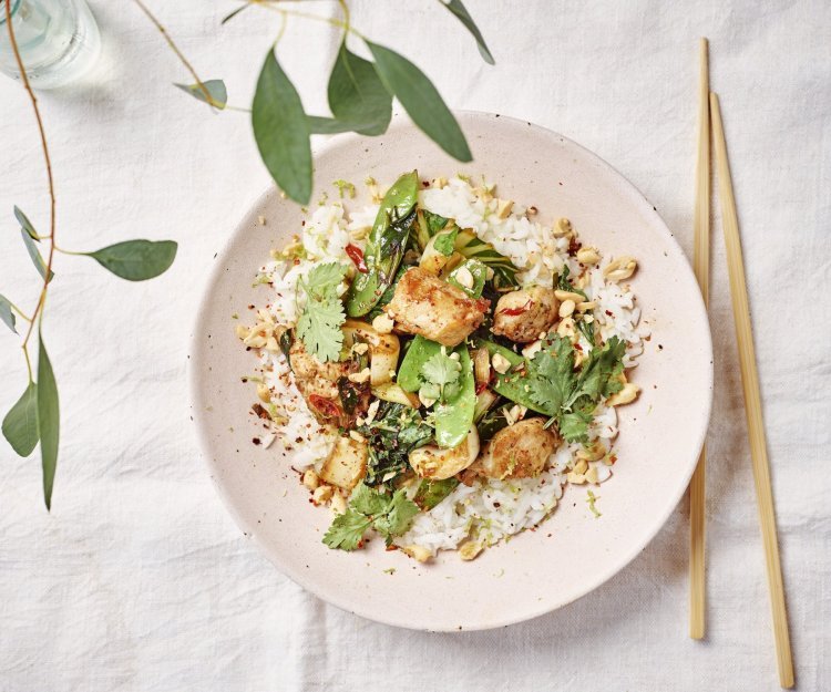 Wok met konijn, paksoi en sluimererwten Een portie food is uitgeschept in een licht roze bord. Het is een portie rijst met daar bovenop de wok van konijn met paksoi en peultjes. Om af te werken zijn er wat pindanootjes toegevoegd en koriander.
