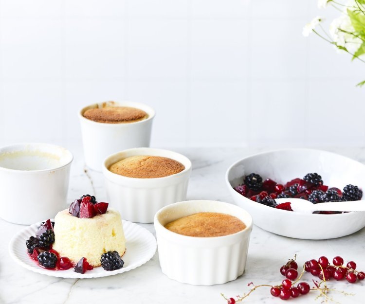 Yoghurtsoufflé met rood fruit Er staan 4 soufflés op tafel, waarvan al eentje uit zijn ovenpotje. Het rood fruit ligt er langs, denk maar aan aardbeien, bessen en pruimen.
