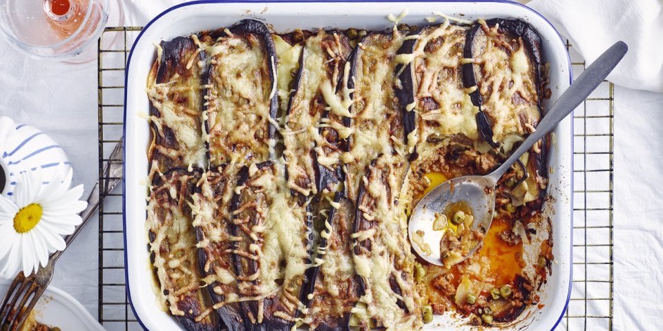 Aardappellasagne met lamsgehakt, aubergine en erwtjes Een grote ovenschotel met aardappellasagne staat op tafel. Er is al een portie uitgedeeld, maar er zijn er nog 5 te verdelen. Perfect te combineren met een glaasje rosé.