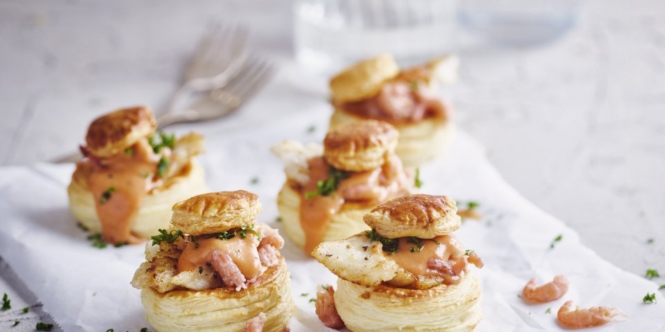 Verschillende bladerdeeghapjes staan op tafel. Ze zijn gevuld met een vol-au-vent op basis van vis, nl steenbolk. 