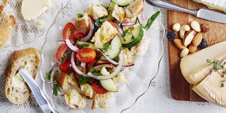 Broodsalade met tomaat en komkommer Een glazen schaaltje, ovaalvormig, gevuld met knapperige croutons, tomatenstukjes en komkommermaantjes.