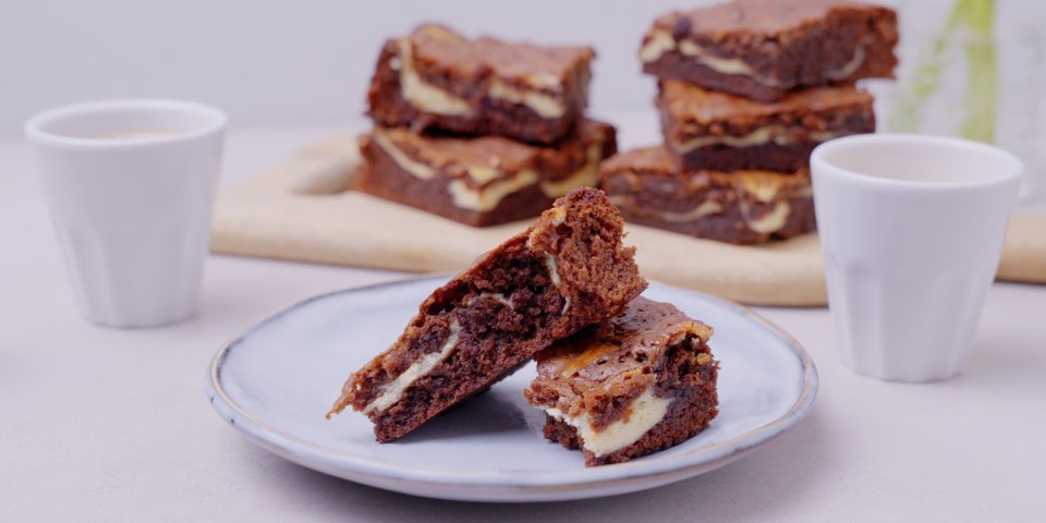 Browniecheesecake De browniecheesecake ligt op een bordje aangesneden. Dit is eigenlijk een brownie in combinatie met cheesecake, zo verkrijg je een marmereffect in je brownie door het mengsel met de roomkaas.