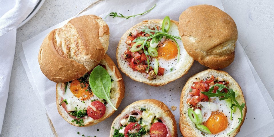 Eieren uit de oven met ham of tomatensalsa Gevulde broodjes met een eitje erin, staan op tafel te blinken! We maakte een versie met gekookte ham, courgette en tomaatjes. En onze tweede is er eentje met pittige tomatensalsa en rucola, heerlijk!