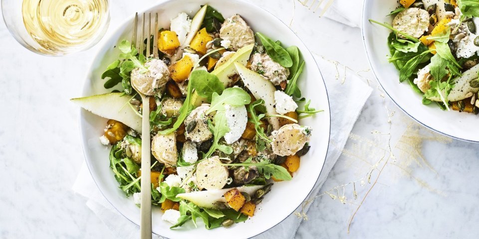 Feestelijke aardappelsalade met pompoen, peer en geitenkaas Een heerlijke aardappelsalade geserveerd in een diep wit bord. De kleuren zijn heerlijk fris en zonnig om je feestmenu te laten stralen. Groen, oranje en wit zijn hier de kleurtoppers.