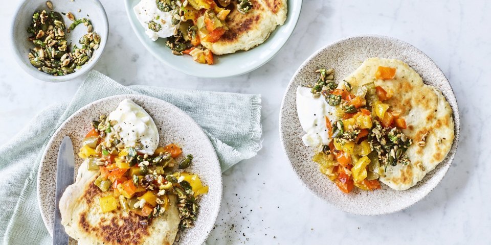 4 bordjes staan op tafel elk gevuld met een stukje flatbread, hier bovenop gestoofde paprikablokjes in 3 kleuren, een stukje burrata en zadencrumble. 