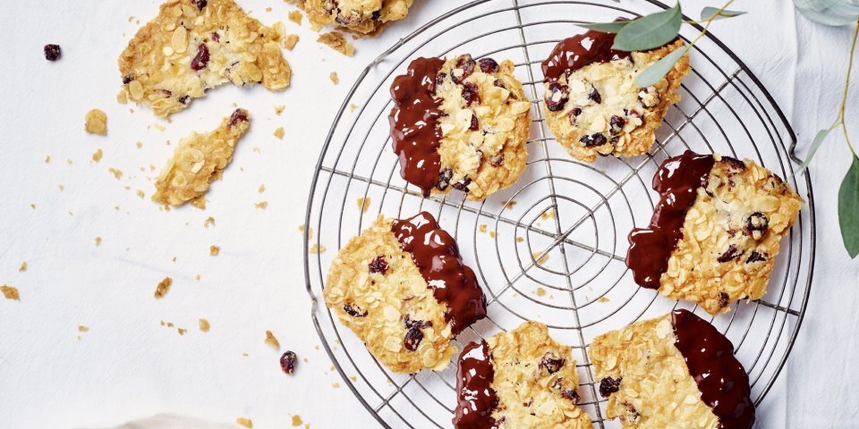 Florentine koekjes met kersen, chili, gember en chocolade Krokante amandelkoekjes liggen af te koelen op een taartrooster. Ze zijn mooi goudgeel gebakken en zijn 1/4 gedipt in gesmolten chocolade.