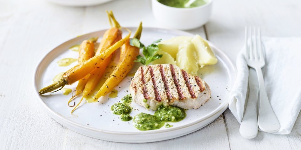 Gegrilde mignonnette met pesto van peterselie en Oud Brugge kaas Een mooi in streepjes gegegrild stukje varkensvlees ligt op een wit bord, geserveerd met gegaarde wortels en gekookte aardappelen. We serveren geen saus bij dit stukje vlees, maar homemade pesto van peterselie en Brugge kaas.