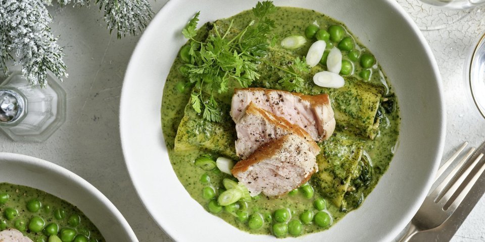 Gevulde cannelloni van spinazie, champignons en kaas in een kruidensausje met kalfsvlees In een diep bord liggen 2 gevulde canneloni, ze liggen in een groen-romig sausje met verse kruiden. Hierbovenop liggen verse kruiden, erwtjes en stukjes kalfsvlees. Een feestelijk en eenvoudig feestgerecht waarbij ieders bord uitlikt.