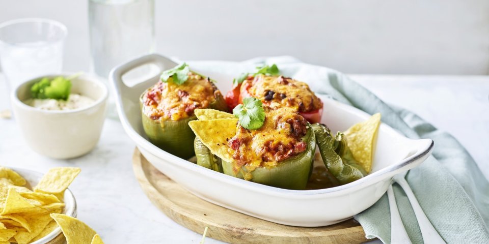 Gevulde paprika met chili con carne Een witte ovenschaal staat op tafel te blinken met opgevulde groene paprika's. Ze zijn gevuld met chili con carne en enkele nacho's. Dit is sowieso een gerechtje dat jong en oud niet koud laat.