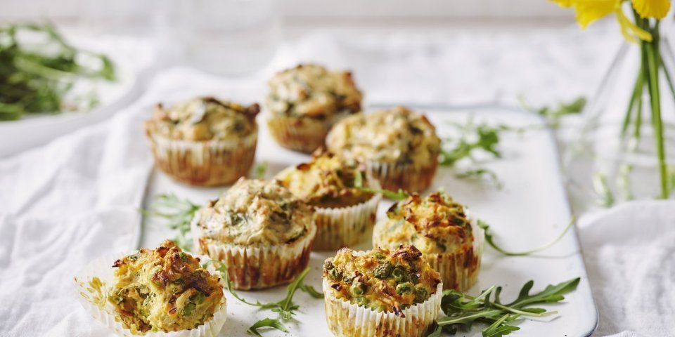 Hartige cupcakes op een dienplateau gepresenteerd. Achteraan staat een vaasje met Narcissen te schitteren.