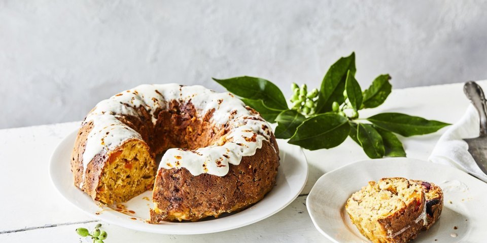 Een tulband cake met groenten als bijgerecht bij je middagmaal, dat is pas een feestmaaltijd! Wij maakten eentje met pompoen, rode biet, Belgische kaas en kastanjes. Hij staat op een witte houten tafel op een wit groot bord, de cake is afgewerkt met een garnering van zure room.