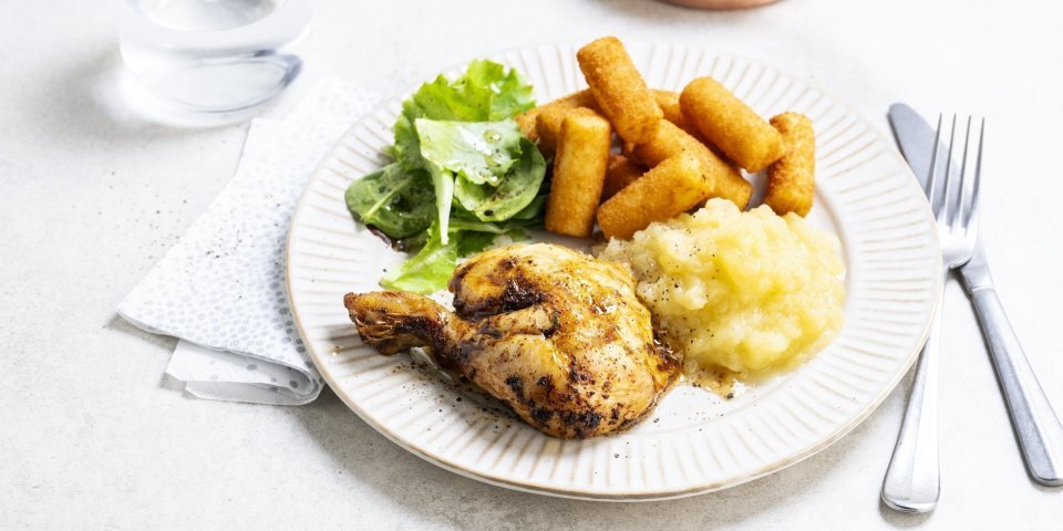 Kip met appelmoes en kroketten Op tafel staat een bord klaar met een gebraden kippenbout, goudgele appelmoes en kroketten. We serveren deze klassieker met nog wat extra sla en ev nog wat appelmoees.