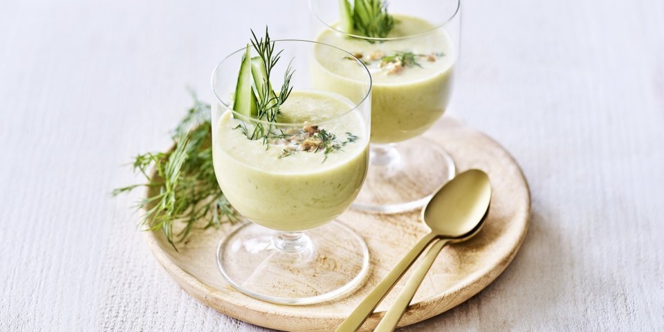 Koude komkommersoep met yoghurt Twee glaasjes gevuld met een koud soepje ogen niet alleen prachtig, ze smaken ook heerlijk fris! Ze heeft een lichtgroene kleur door de komkommer, prei en yoghurt. Het soepje is afgewerkt met walnoten, dille en staafjes komkommer.