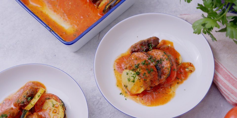 Ovenschotel met groenteschijfjes, gehakt en tomatensaus Twee bordjes staan op tafel met een uitgeschepte portie vanuit onze ovenschotel. We maakten een ovenschotel met plakjes groenten en schijfjes gehakt met tomatensaus.