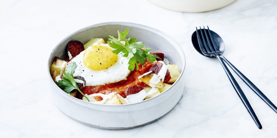 Patatas bravas opgediend in een diep bordje met tomatensaus, spiegelei, verse sla en yoghurtdressing. Ik wil er meteen aan beginnen! 