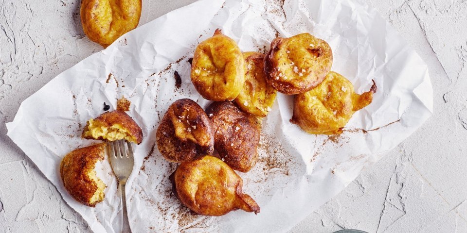 Op het aanrecht liggen enkele pompoenbeignets op een wit boterpapiertje. Ze hebben een mooie oranje gloed, net gouden beignets. Er ligt een vorkje langs meteen te prikken en te eten. 