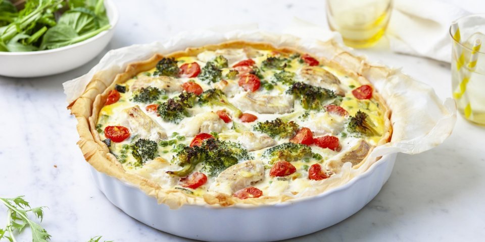 Het lijkt alsof de quiche net uit de oven komt. Ze staat nog ongesneden op het aanrecht klaar om aan te snijden en te smullen van deze hartige taart met broccoli, tomaatjes en schelvis.