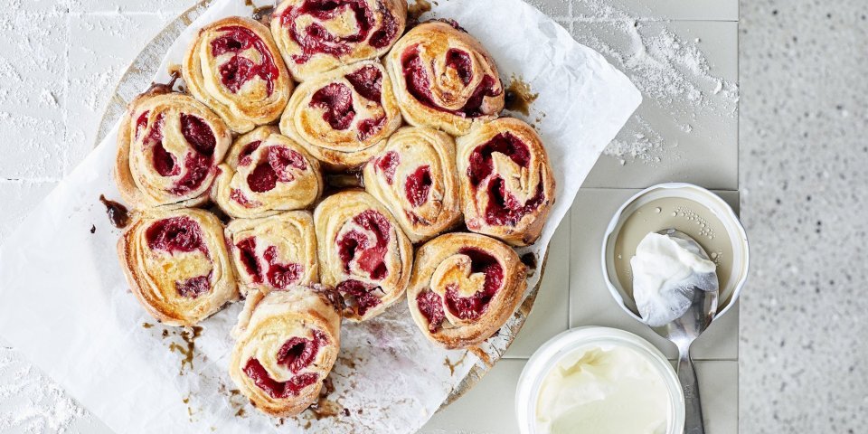 Rolletjes gemaakt van beslag met yoghurt, gevuld met framboosje. De rolletjes liggen tegen elkaar in een cirkelvorm. Heerlijke kleuren om naar te kijken en nog beter om op te eten.