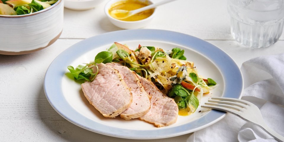 Salade met varkensgebraad en mosterddressing Er staat een bordje op tafel, gevuld met de kleurrijke én rijke salade. Er liggen ook enkele sneetjes varkensgebraad bij. Je kan extra salade scheppen en vinaigrette.