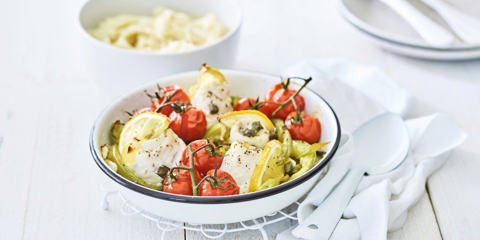 In een ronde ovenschaal liggen de tongrolletjes te blinken. De ovenschotel werd aangevuld met kerstomaatjes in trosvorm en stukjes groene paprika. Er werden ook partjes citroen toegevoegd voor een extra frisse smaak. In de achtergrond is een kommetje gevuld met puree.