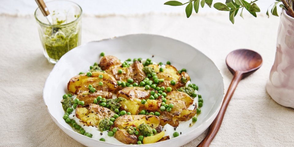 Smashed potatoes met plattekaas, erwtjes en pesto Een heerlijk bordje gevuld met plattekaas met hierop de de krokante 'platgestampte' aardappelen. De groene erwtjes en toefjes pesto zorgen voor een mooie kleur in het bordje.