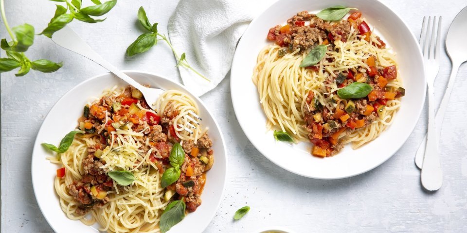 Spaghetti bolognaise Twee borden gevuld met huisgemaakte spaghetti bolognaise. Afgewerkt met basilicumblaadjes die zorgen voor extra smaak en kleur in je bord.