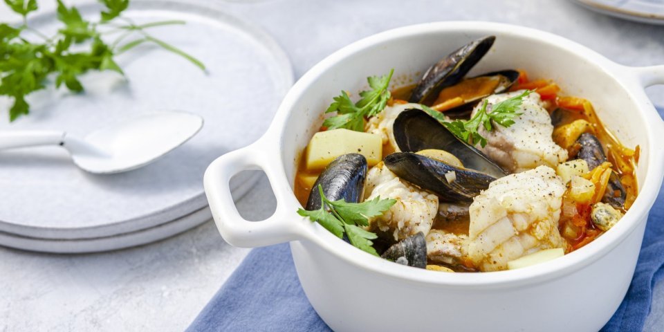 Een stoofpotje van vis, mosselen en passata klaargemaakt in een grote witte kookpot. Vakantie in je kookpot! 