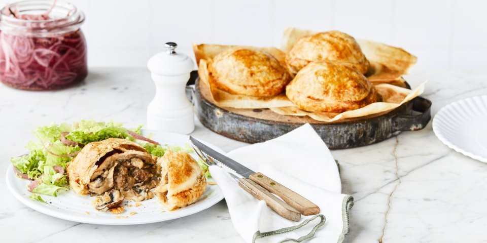 Achterin de foto staat een schaal met hierop 3 vol-au-vent taartjes. Vooraan in het beeld ligt er één taartje aangesneden. Met wat sla erbij en ingemaakte rode ui.