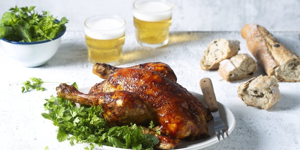 Volledige kip op de BBQ met een frisse kruidensalade Een volledige kip op de BBQ op een blikje bier klaargemaakt, dit noemen we canned chicken. Deze kip kreeg een kruidige jas aan door de BBQ-saus. Ze ligt op een kruidige salade klaar om te knippen in stukken en op te peuzelen.