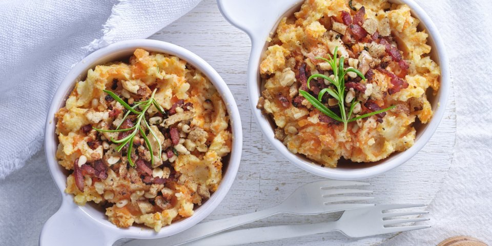 Winterse puree met krokante topping van spek en noten Op tafel staan 2 potjes uitgeschept als bijgerecht. Ze zijn gevuld met een heerlijke aardappelpuree met wortel en afgewerkt met stukjes spek, noten en salie.