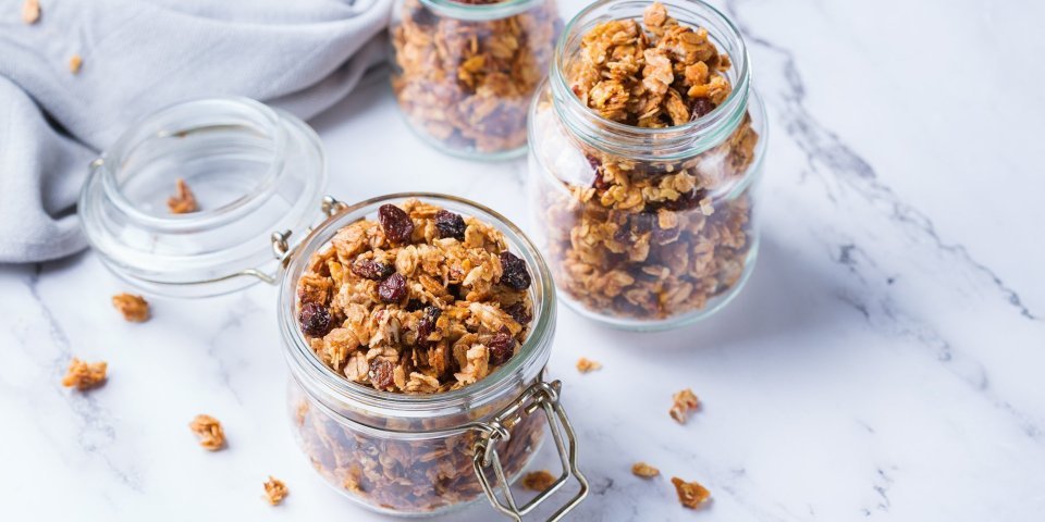 Homemade granola in 2 bokalen op het marmere aanrecht. 