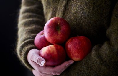 Vrouw houdt 4 appels vast tegen haar midden. Net zo zorgzaam als een kind dat ze zou dragen. 