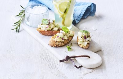 Bruschetta met perensalsa en blauwe schimmelkaas liggen op een marmer schaaltje samen met een homemade rozemarijnlimonade met peer. 