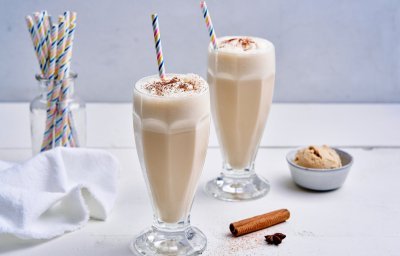 Op tafel staan twee grote glazen gevuld met milkshake, maar niet zomaar milkshake. Dit is er eentje met huisgemaakte chai latte en afgewerkt met slagroom en een snuifje kaneelpoeder. 