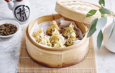 Er staat een stoommandje op het marmere aanrecht waarin verschillende dumplings liggen. Er staat bovenaan een dipsausje op basis van sojasaus en een chinees kannetje. 