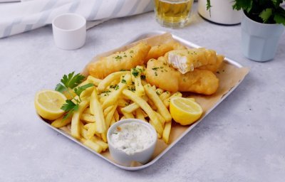 Een metalen schotel is gevuld met homemade knapperige frietjes, fishsticks en verse tartaarsaus. Het gerechtje is afgewerkt met verse gesnipperde peterselie.