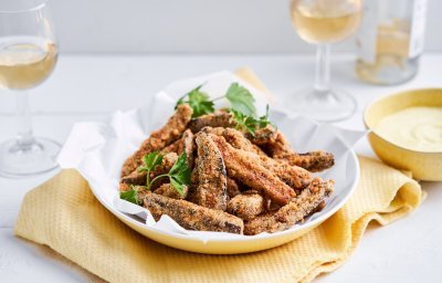 Op de tafel staat een heerlijk krokant hapje van aubergine. Ja, krokante auberginefrietjes met een currydipsausje. Wij serveren hem met een glaasje rosé, ideaal als starter van heerlijke maaltijd. 