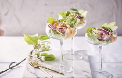 Drie garnalencocktails staan geserveerd op een marmer aanrecht, in mooie wijnglazen met een brede opening bovenaan. Er liggen gouden vorkjes naast om het feestgehalte een extra boost te geven. 