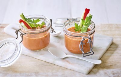 Twee bokaaltjes met gazpacho staan op een marmer plankje, een ideaal alternatief voor te weinig glazen. We gaven de gazpacho een feestlook met staafjes komkommer en paparika in het bokaaltje te laten op springen.  