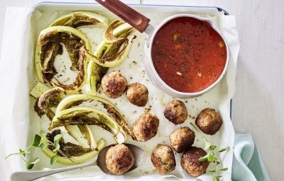 Gegrilde bloemkoolbladeren liggen op de ovenschaal met gehaktballetjes en tomatensaus in een sauspannetje. 