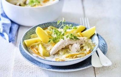 Op een witte houten tafel staat de kookpot vol waterzooi, er is een bordje uitgeschept met hierop de gekookte aardappelpartjes geschikt. Het gerechtje is afgewerkt met een takje verse kervel. 