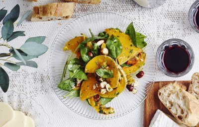 Een glazen bordje staat op tafel met geroosterde partjes pompoen. De salade krijgt een mooi groen kleurtje door de verse spinazie, hij is afgewerkt met enkele hazelnoten. Op en top een herfstsalade boordevol smaak.