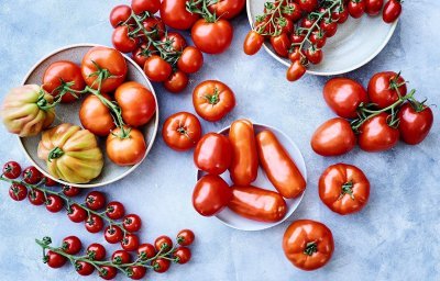 Op het keukenaanrecht, in betonlook, liggen verschillende variëteiten van tomaten. 50 tinten rood in 1 beeld. 